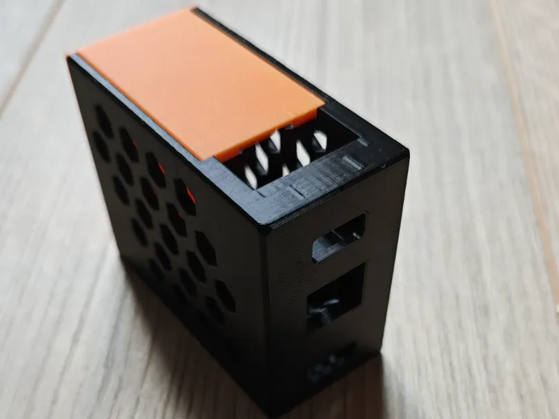 A second 3D-printed case for the same two boards: a black box with a hex-vented side, an orange lid and cutouts for HDMI and Ethernet